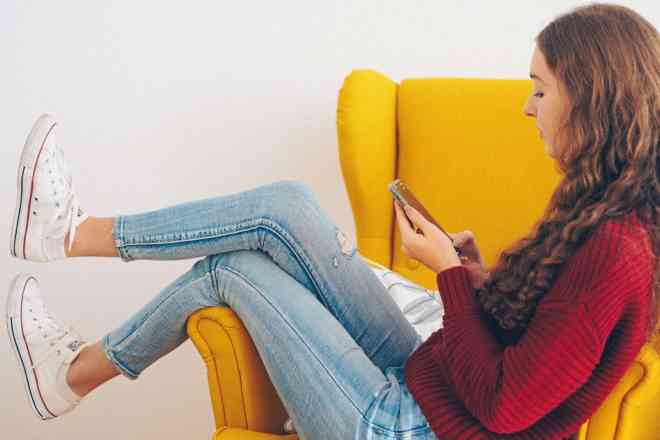 girl sitting in armchair on phone and wondering is wordpress good for ecommerce
