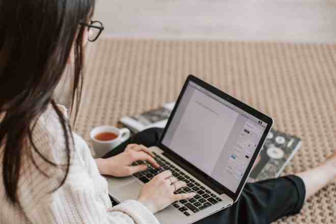 woman sitting on floor typing on laptop